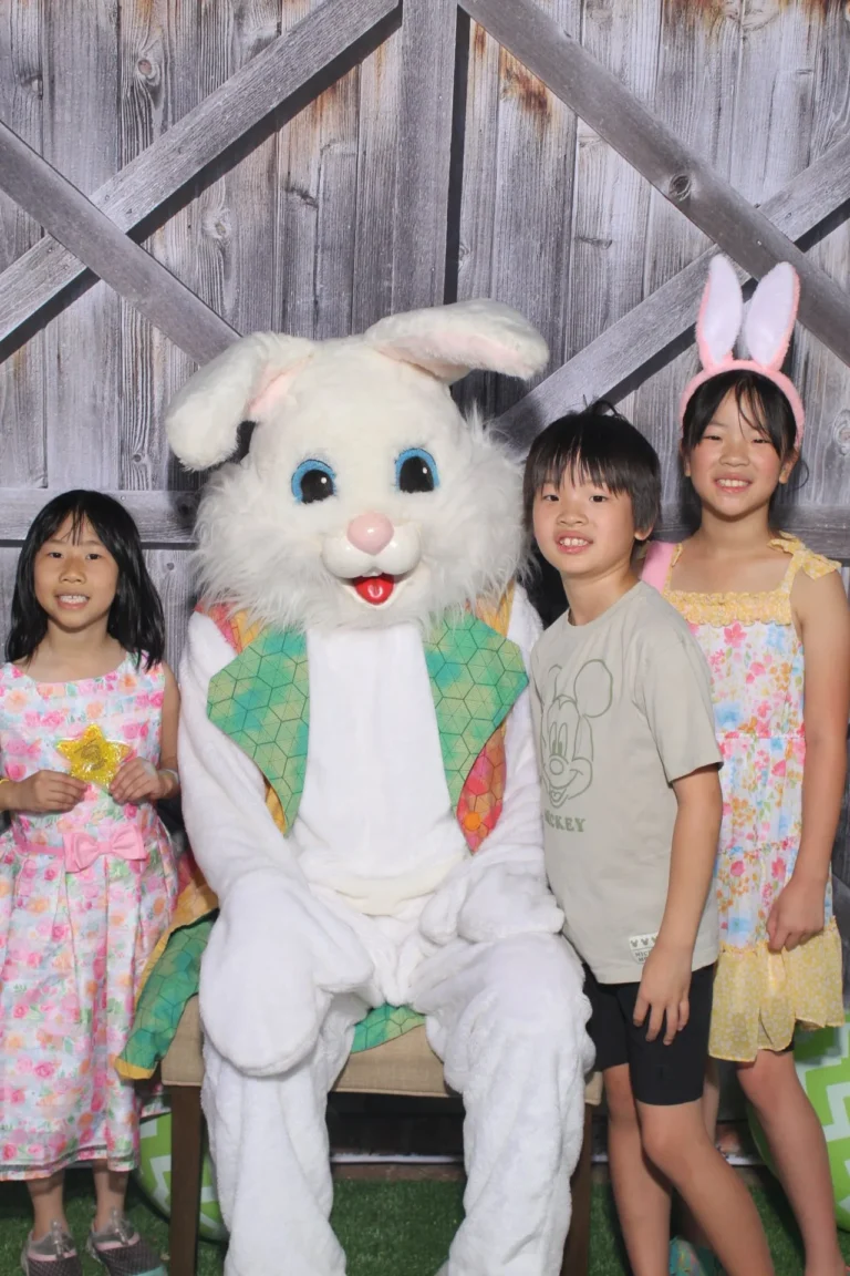 Family posing with the Easter bunny mascot at a barn door backdrop during a community event