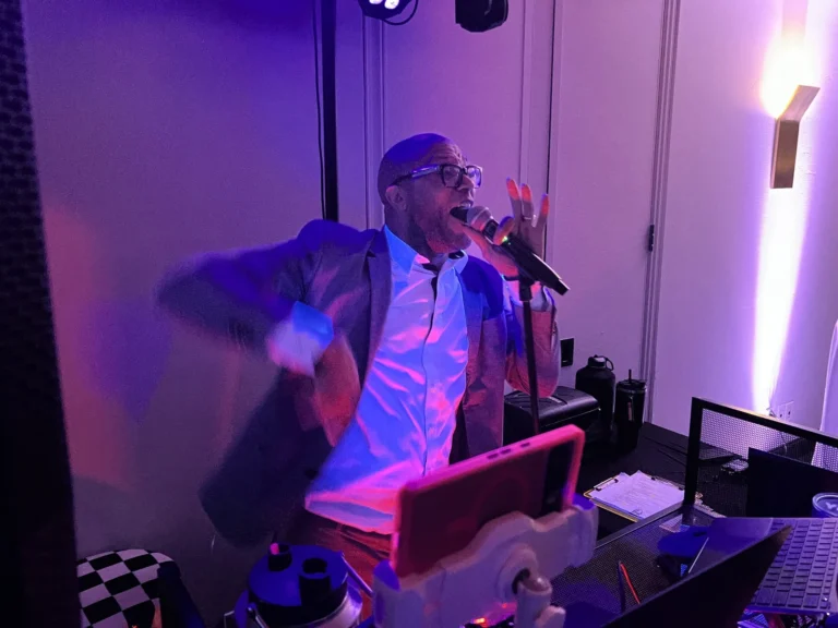 Hype Man Entertainment emcee working the microphone under magenta uplighting on a checkered dance floor