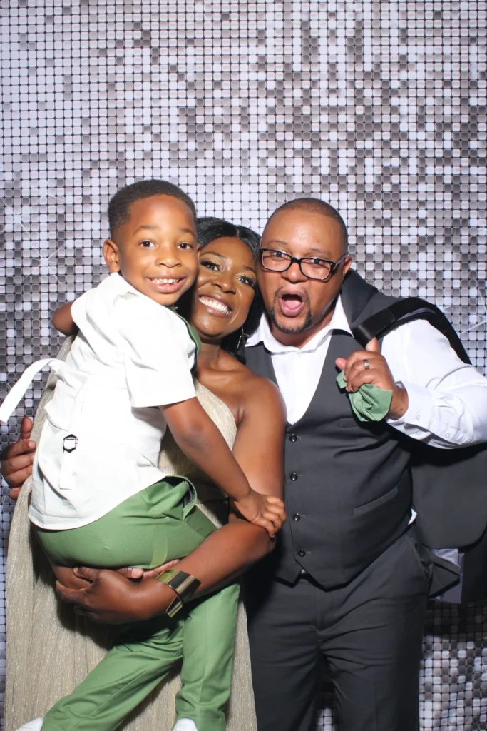 Father and son posing together at a silver sequin photo booth backdrop