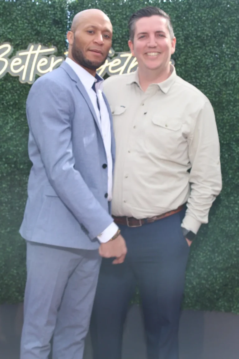 Kelvin and Taylor of Hype Man Entertainment posing at a greenery wall with a Better Together neon sign