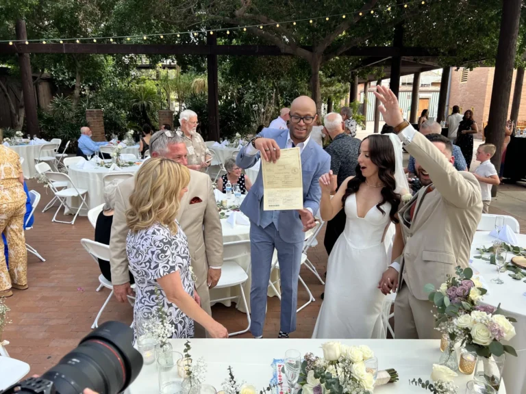 Newlyweds embracing beside their witnesses after signing the marriage license outdoors
