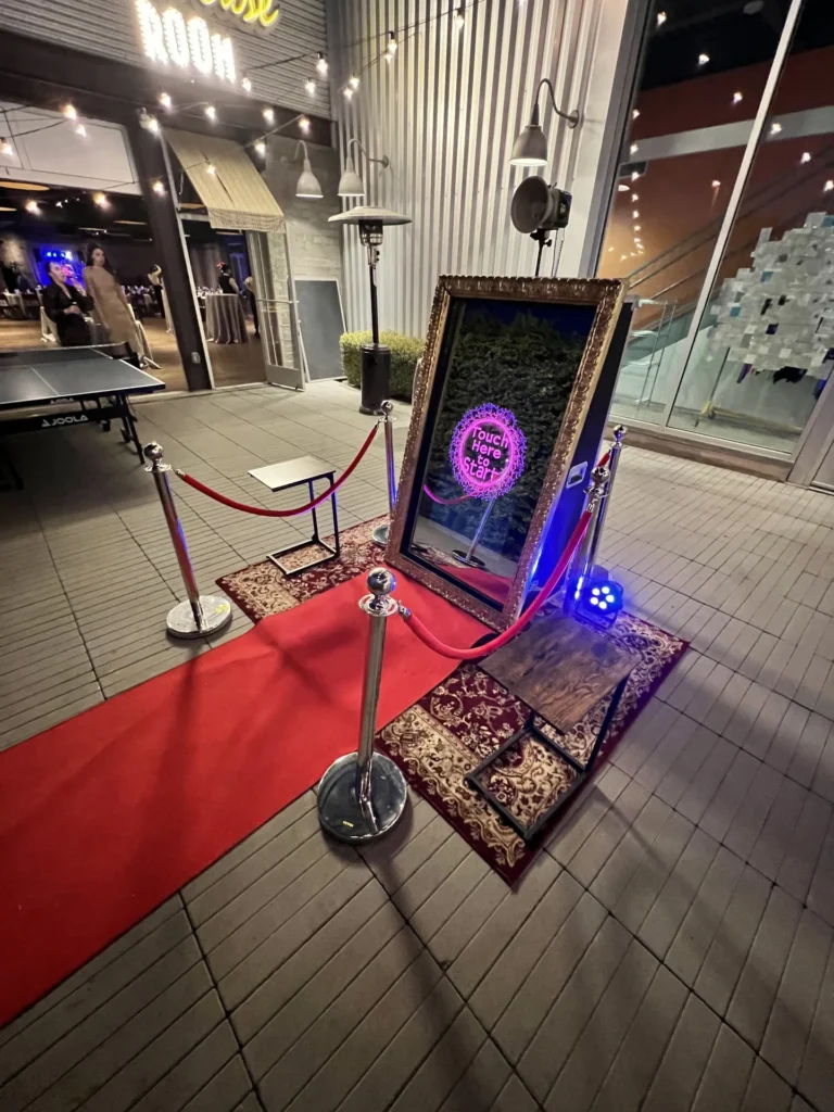 Mirror photo booth with a red carpet runner and rugs set up in an outdoor courtyard venue